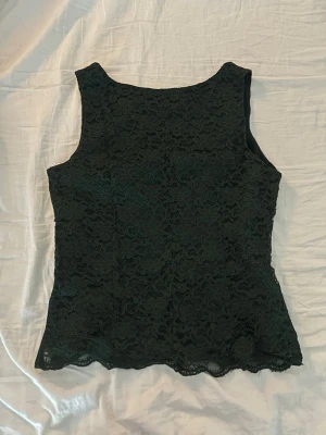 Mörkgrön spetsblus  - Säljer en mörkgrön blus från H&M i storlek 38. Super snygg topp med blommigt spetslager, enligt mig funkar den att ha som vanligt men den är även jätte fin om man vänder på den! 