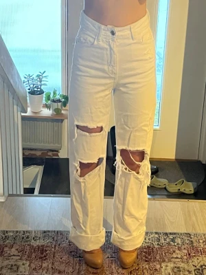 Vita ripped jeans från Zara - Säljer ett par snygga vita jeans från Zara med hög midja och raka ben. 