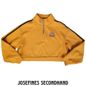 Gul croppad tröja från H&M - Gul croppad mjukiströja från H&M. Är i Kill Bill style med dragkedja. Har ett broderat märke där det står "Chase the rainbow" med en regnbåge. Köpt secend hand