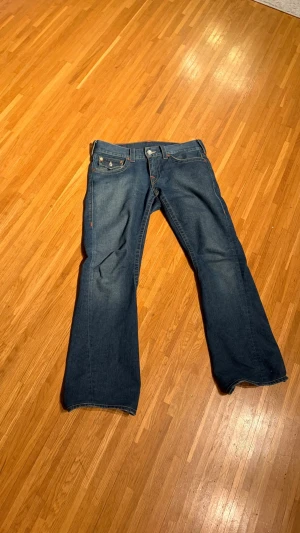 True Religion Joey blå bootcut jeans - Säljer ett par klassiska True Religion Joey (bootcut)  jeans i storlek W30 L 33. Väldigt sparsamt använda och har en grym passform. Skicka prisförslag!