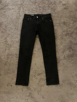 Levi's 511 svarta slim jeans - Säljer ett par svarta Levi's 511 jeans med slim fit. Klassisk femficksmodell med Levi's patch bak och röd logotagg på bakfickan. Jeansen är i stretchigt denimtyg och har slim passform hela vägen ner.