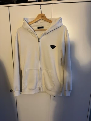Vit Prada zip hoddie - Säljer för den är för liten för mig. Skriv vid funderingar. Pris kan diskuteras vid snabb affär👍