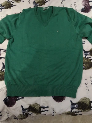 Grön stickad tröja från Boomerang - Säljer en grön stickad tröja från Boomerang i storlek M. Tröjan har v-ringning, ribbade muddar och en liten broderad logga på bröstet. Perfekt för dig som gillar klassisk och enkel stil. I nyskick använd ett fåtal gånger.