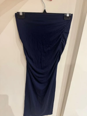 Mörkblå långkjol från Gina Tricot - Säljer en mörkblå långkjol från Gina Tricot i storlek XS. Kjolen har en tight passform och är gjord i mjukt bomullsmaterial. Snygg rynkning på sidan ger en cool och trendig look. Perfekt att styla med crop top eller oversized hoodie.