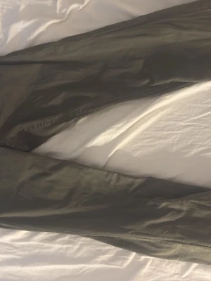 Olivgröna byxor från Gina tricot - Snygga olivgröna byxor från Perfect Jeans i storlek 36. Byxorna är boot cut, två bakfickor med lock och knapp, samt bälteshällor. Materialet känns mjukt och stretchigt, perfekt för en avslappnad look. Använda en gång bara! Og pris:500kr