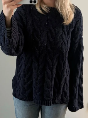 Mörkblå kabelstickad tröja - En mörkblå kabelstickad tröja med rund hals från Gina Tricog 