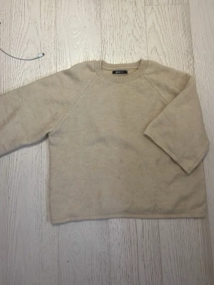Beige/gul stickad tröja från Gina Tricot - En enkel och stilren beige stickad tröja från Gina Tricot. Tröjan har rund halsringning, långa ärmar och är gjord i ett mjukt material som passar perfekt till kyligare dagar. Snygg att matcha med jeans eller kjol.