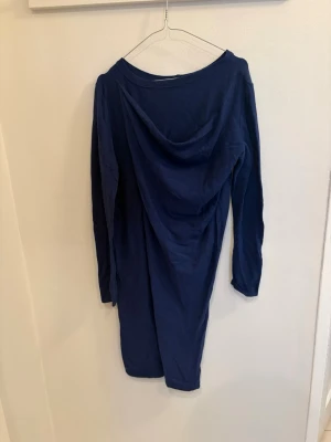 Mörkblå långärmad klänning - En enkel och stilren mörkblå klänning från ICE. Modellen är rak med lång ärm och mjukt, stretchigt material. Perfekt för dig som gillar minimalistisk stil och vill ha något bekvämt men ändå snyggt.