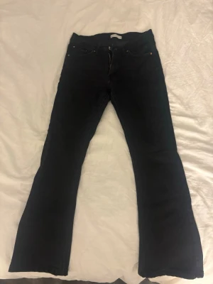 Svarta bootcut jeans från Perfect Jeans - Säljer ett par svarta jeans från Perfect Jeans i storlek 36. Modellen har bootcut-ben och klassisk femficksdesign med dragkedja och knapp framtill. Jeansen är tillverkade i ett mjukt jeansmaterial och har en snygg, enkel look.
