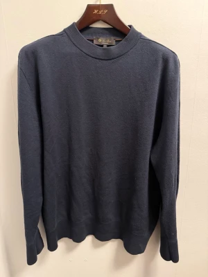 Loro Piana tröja  - Klassisk mörkblå tröja från Loro Piana i 100% virgin wool. Enkel och stilren design med rund halsringning och ribbade muddar. Perfekt för dig som gillar tidlös och lyxig stil. Tillverkad i Italien.
