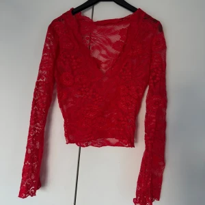 Spets topp - En röd långärmad spetstopp, genomskinlig så man får ha bh under! Storlek M men liten i storlek så skulle säga en S