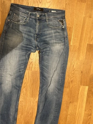 Replay W30 L32 - Säljer ett par Replay Rocco jeans i klassisk blå tvätt med snygga slitningar. Jeansen har raka ben, fem fickor och detaljerade sömmar på bakfickorna. Jeansen är som nya. Hör av vid intresse!