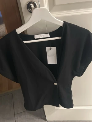 Topp  från Sisters Point - Svart omlottblus från Sisters Point med kort och en snygg v-ringning. Storlek M men passar en S lika bra !!💗