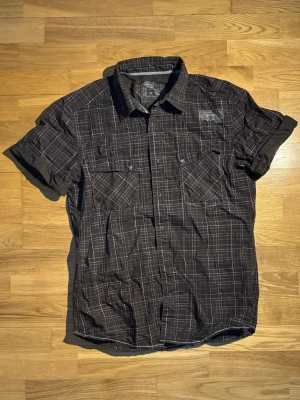 Rutig kortärmad skjorta från Esprit - Säljer en svart och vit rutig skjorta från Esprit med korta ärmar och två bröstfickor med knappar. Skjortan har klassisk krage och knappstängning framtill. Perfekt till sommarens alla tillfällen.