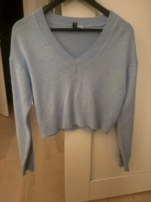 Ljusblå croppad stickad tröja H&M - Supersöt ljusblå croppad stickad tröja från Vero Moda. Tröjan har v-ringning, långa ärmar och bred ribbad kant vid ärmslut och nederkant. Perfekt till jeans eller kjol för en chill look.