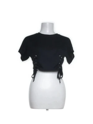  croppad topp med snörning  - Säljer en svart croppad topp från Boohoo med korta ärmar och cool snörningsdetalj i sidorna!!passar mig med xs/s