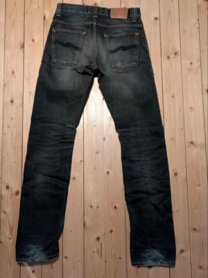 Nudie average Joe - Säljer ett par grå Nudie jeans i modellen average Joe vilket är slim/straight. Se bild för passform. Knappen högst upp sitter lite löst men ramlar inte av och går att få reparerat gratis hos Nudie jeans. De är även slitna vid hälarna vilket enligt mig endast gör dem snyggare. Storlek w28 l34 men går att korta ner gratis hos Nudie. 