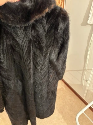 Svart pälsjacka med krage - Säljer en svart pälsjacka med fluffig krage och helsvart insida. Jackan har långärmade ärmar och är i en loose passform, perfekt för dig som vill ha en riktigt maffig look. Materialet är äkta  päls och jackan är helsvart med snyggt mönstrad yta.