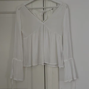 Spetstopp - Långärmad tunn topp med spetsdetalj i ryggen.