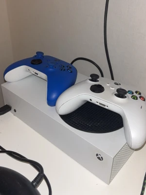 Xbox Series S med två kontroller - Säljer en Xbox Series S i fint skick med två trådlösa kontroller (vit och blå). Konsolen fungerar utmärkt och är perfekt för digitalt spelande. Inga synliga defekter, endast mindre ytliga märken på den vita kontrollen. Perfekt för både solo- och multiplayer-spel.