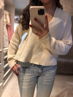 Ribbad ljusbeige stickad tröja - Säljer en ribbad stickad tröja i ljusbeige med v-ringad hals och långärmad passform. Tröjan har en loose fit och är perfekt för dig som gillar en enkel men snygg look. Materialet är mjukt och skönt mot huden och passar till jeans eller kjol.