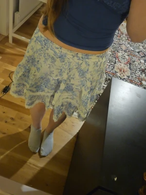 Blommig kortkjol med spetskant - Säljer en söt kortkjol med blått blommönster på vit botten. Funkar perfekt på sommarhalvåret