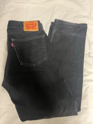 Svarta Levi's 505 jeans, W31 L32 - Svarta Levi's 505 jeans med klassisk femficksdesign och röd Levi's-tag på bakfickan. Jeansen har rak passform och är tillverkade i slitstarkt bomullsmaterial. Perfekt för dig som gillar en enkel och tidlös look.