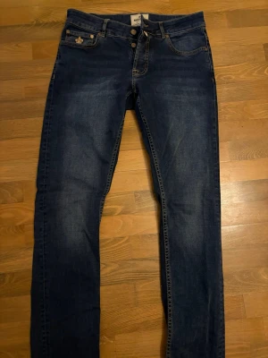 Mörkblå jeans från Morris - Mörkblåa jeans med den klassiska fem fickor designen. För dig som vill ha en stilren look. Dem är i nytt skick. Storlek 29 32