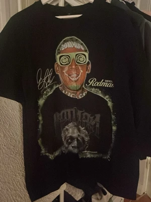 Svart t-shirt med Dennis Rodman-tryck - Cool svart t-shirt med stort tryck av Dennis Rodman och grafiskt motiv framtill. T-shirten är oversized i storlek M och är även en tung och lite tjockare t shirt 