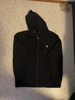 Polo ralph lauren hoodie zip - Säljer en Polo Ralph Lauren hoodie med zip i svart med vit logga 🤍🖤 Fick den i jul 🎄 men säljer eftersom den tyvärr är lite för stor för mig. Hoodien är i mycket fint skick, knappt använd 👌 Säljer för att köpa samma modell i storlek S. Hör av dig vid intresse! 📩✨ 