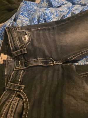 Svarta jeans från Gina Tricot, stl 170 - Säljer ett par svarta jeans från Gina Tricot med snygga slitningar och kontrastsömmar. Klassisk femficksmodell med knapp och dragkedja fram. Jeansen har en rak passform och är tillverkade i jeansmaterial med lite stretch.