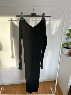 Svart ribbad långklänning - Svart figurnära stickad klänning från hm, unik v-ringning som ej är djup, fina detaljer i ärmarna, klänningen är vadlång, stl xs passar även s då den är strechig 