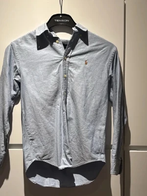 Ljusblå skjorta från Ralph Lauren - Säljer en klassisk ljusblå skjorta från Ralph Lauren med broderad logga på bröstet. 