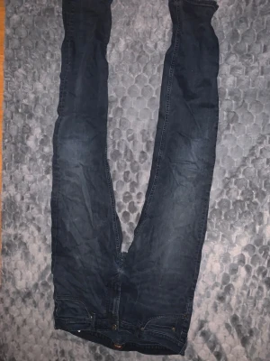 Mörkblå jeansbyxor W34 L34 - Snygga mörkblå jeansbyxor i klassisk rak modell med fem fickor och knappgylf. Materialet är slitstarkt jeans och passformen är normal. Perfekta för dig som gillar enkel och stilren denim-look.