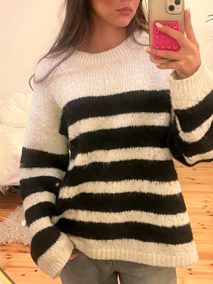 Randig stickad tröja från BikBok - Säljer en mysig stickad tröja från BikBok i storlek M. Tröjan har breda svarta och vita ränder, rund hals och långa ärmar. Perfekt för dig som gillar en chill och avslappnad stil med lite oversized känsla.