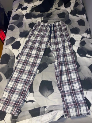 Rutig loungebyxa från Time to Lounge - Säljer ett par chill rutig loungebyxor från Time to Lounge i storlek 170. Byxorna har snörning i midjan och är gjorda i mjuk bomull. Färgerna är vit, blå och röd, med ett klassiskt rutmönster som ger en avslappnad vibe.