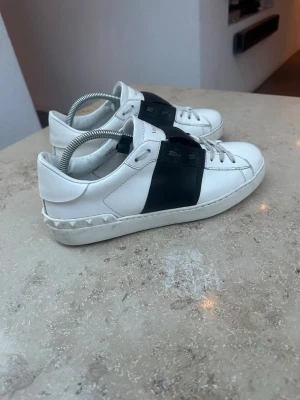 Valentino Garavani sneakers med svart detalj - Snygga vita skor från Valentino Garavani. Skorna är använda. Dustbag ingår vid köp. Storleken är 41 men passar även 42. Säljer pågrund av att dem har blivit för små för mig. 