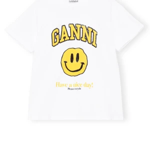 Vit Ganni t-shirt  - Vit t-shirt från Ganni med stort gult smileytryck och texten 'Have a nice day!'. Tröjan har inte kommit till användning så därav i väldigt bra sick. 