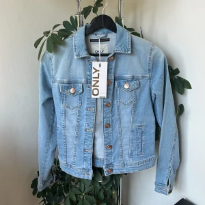 Ljusblå jeansjacka från ONLY -  Jättefin ljusblå jeansjacka från ONLY, storlek EU34. Helt oanvänd med kopparknappar. Sidofickor och bröstfickor, passar bra vid varmare väder och jätte snygg färg att matcha med jeans!