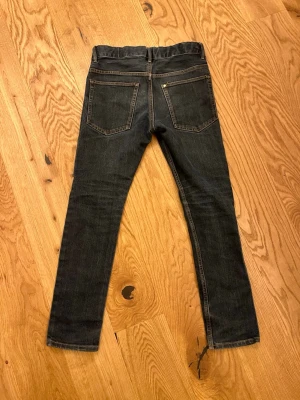 Mörkblåa skinny jeans med fem fickor från H&M  - Snygga mörkblåa skinny jeans med klassisk femficksdesign och knappstängning fram. Jeansen har en mörk tvätt och smal passform som sitter tajt längs benen. Perfekta för dig som gillar en stilren och enkel look.