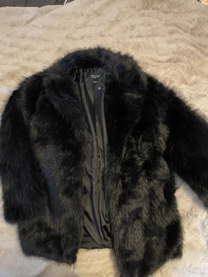 Svart pälsjacka från lager 157 - Snygg svart pälsjacka från lager 157  i storlek XS/S. Jackan har en fluffig och lyxig känsla med långärmad design och klassisk krage. Perfekt för dig som vill sticka ut med en statementjacka i vinter.