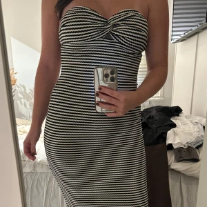 Randig axelbandslös klänning - Säljer en svartvit randig axelbandslös långklänning från Missguided. Klänningen har en twistad detalj vid bysten och är figurnära med stretchigt, stickat material. Storlek s/m, aldrig använd 🩷