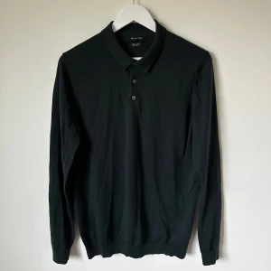 Mörkgrön pikétröja i merinoull Massimo Dutti - Mörkgrön långärmad pikétröja från Massimo Dutti i mjuk och tunn merinoull. Klassisk krage med två knappar framtill och ribbade muddar vid ärmslut och nederkant. Perfekt för dig som gillar stilrena och enkla plagg med premiumkänsla. 5J10