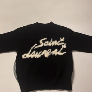 Svart YSL stickad tröja - Säjer dena stilrena stickade  tröja från Saint Laurent. Perfekt tröja för höst o vintern då den är både skön o varm. Tveka inte att höra av dig 