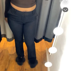 Svarta bootcut kostymbyxor - Snygga svarta kostymbyxor med bootcut passform och hög midja. Byxorna har klassiska fickor fram och hällor för bälte. Perfekta för dig som gillar en stilren look med lite utsvängda ben. Materialet känns mjukt och har en lätt stretch.