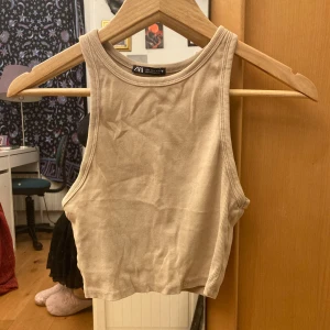 Beige ribbad linnetopp från Zara - Säljer en beige croppad linnetopp från Zara i storlek L, men liten i storlek och är mer som en M-S. Toppen är av ett mjukt, stretchigt och ribbat bomullstyg. Använd få gånger. Frakt ingår ej