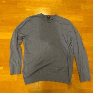 Blå slim fit tröja från H&M - En stilren blå tröja från H&M i slim fit-modell. Tröjan har rund halsringning, långa ärmar och ribbade muddar vid ärmslut och nederkant. Perfekt för dig som gillar en enkel och clean look.