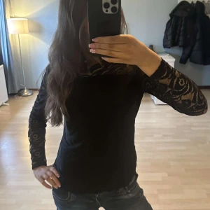 Svart spetsblus - Elegant svart blus med spetsdetaljer över axlar och ärmar. De står att den är i L men skulle säga att den sitter mer som en M💗 Den sitter väldigt skönt mot huden🫶🏻