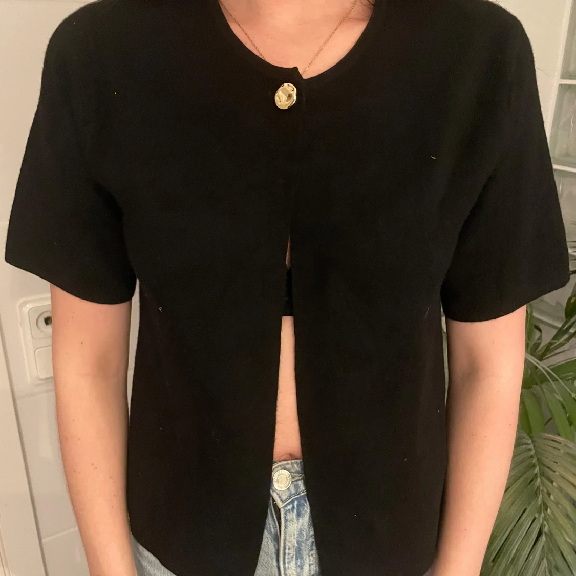 Svart bolerotopp med guldknapp