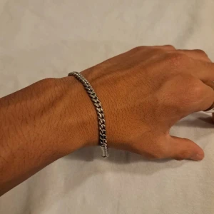 Armband - Silverfärgad  - Stilrent armband med klassisk kedjedesign i silverfärgad metall. Låset är ett smidigt karbinlås som gör det enkelt att ta av och på. Perfekt för dig som gillar minimalistiska accessoarer med lite edge. Passar både killar och tjejer som vill ha något snyggt på handleden.